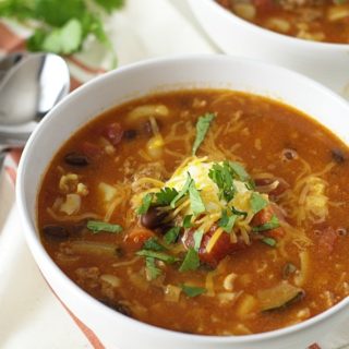 Two bowls of chili mac soup on a white table.