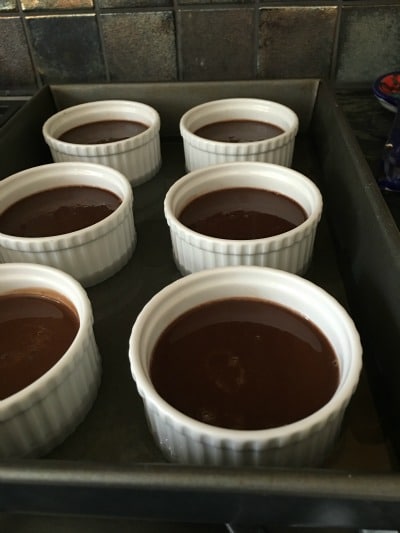 6 chocolate custard desserts in a hot water bath, ready for baking