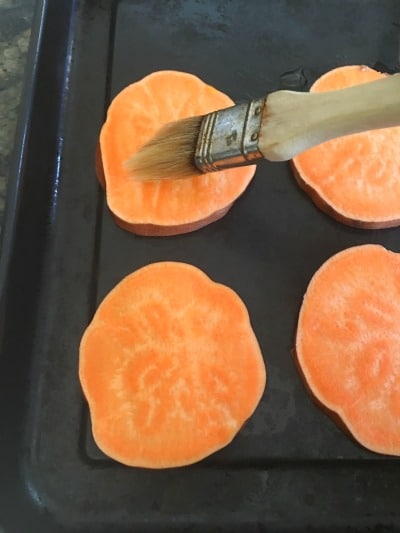 Brushing Sweet Potatoes with olive oil.