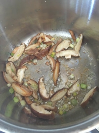 Shiitake and green onions cooking in a frying pan
