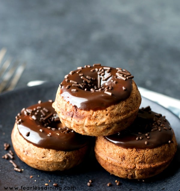 Gluten Free Chocolate Donuts stacked on a black plate.