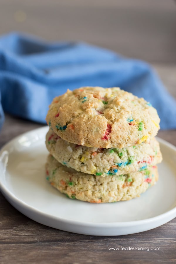 Three funfetti cookies stacked on a white plate.