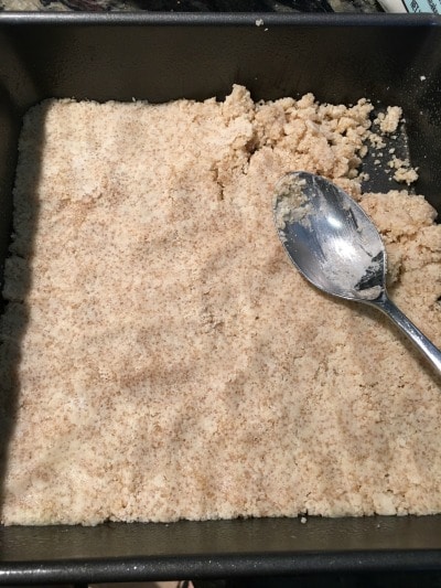 Adding graham cracker crust to pan.