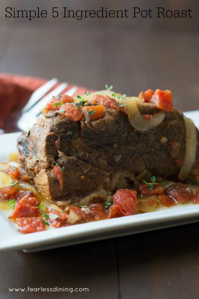 5 Ingredient Crock Pot Roast on a platter with onion and tomatoes on top