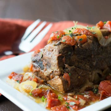 A large platter with a large chuck roast on it.