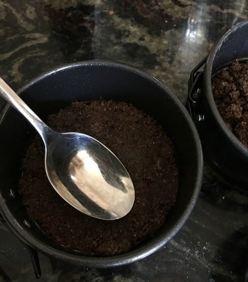 Pressing down crust with a spoon in the springform pan.