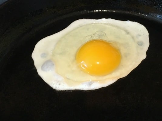 Frying a sunny side up egg on a cast iron skillet.