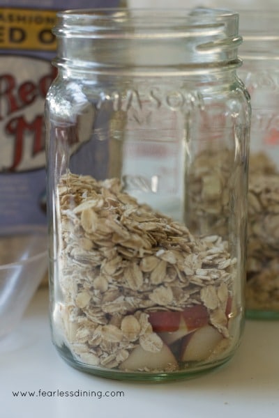 A mason jar filled with oats and cut up apples.