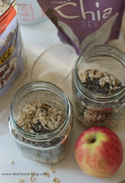 Add oats and chia in mason jars next to an apple.