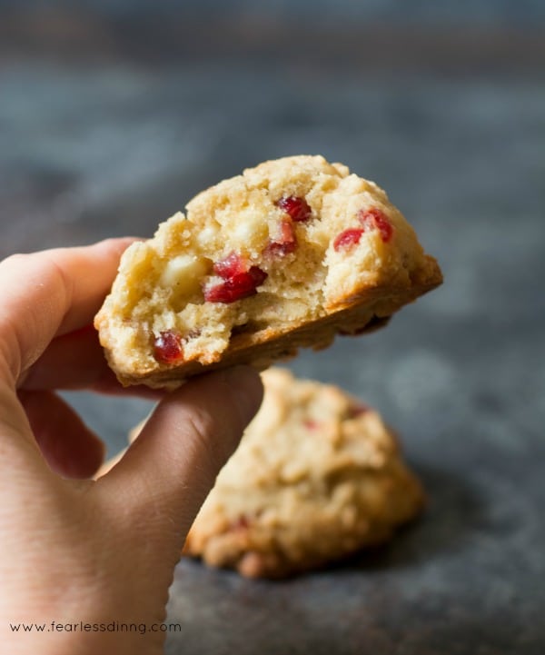 Gluten Free Cranberry White Chocolate Chip Cookie with a hand holding it up. A bite was taken out of the cookie
