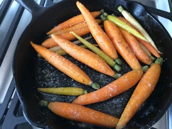 Carrots cooking in a cast Iron skillet.