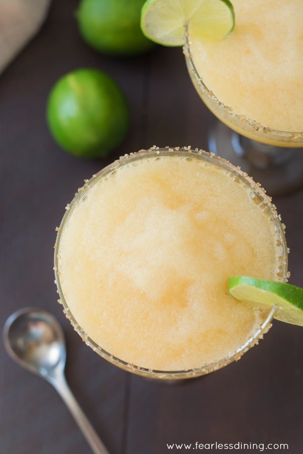 Top view of a glass of frozen peach margarita with fresh limes.
