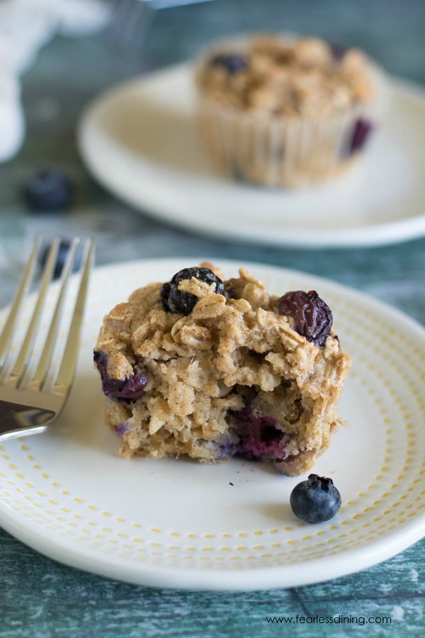 A blueberry oatmeal muffin on a plate with a bite taken out.