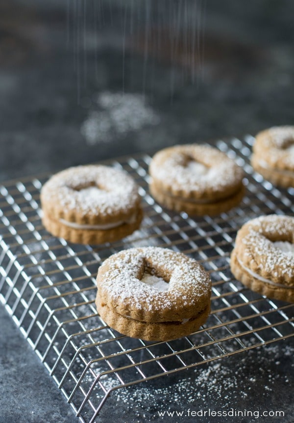 Gluten free gingerbread linzer cookies on a cooling rack with powdered sugar on top.