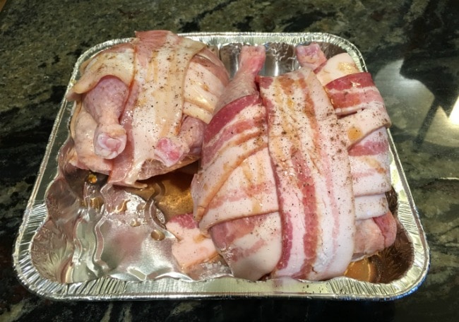 Cornish game hens wrapped in raw bacon, ready to bake.