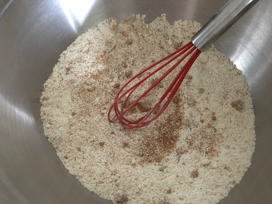 Donut dry ingredients mixed in a bowl. A whisk in in the bowl.