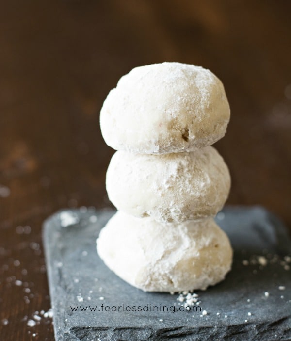 A stack of three Russian tea cookies on a slate tile.