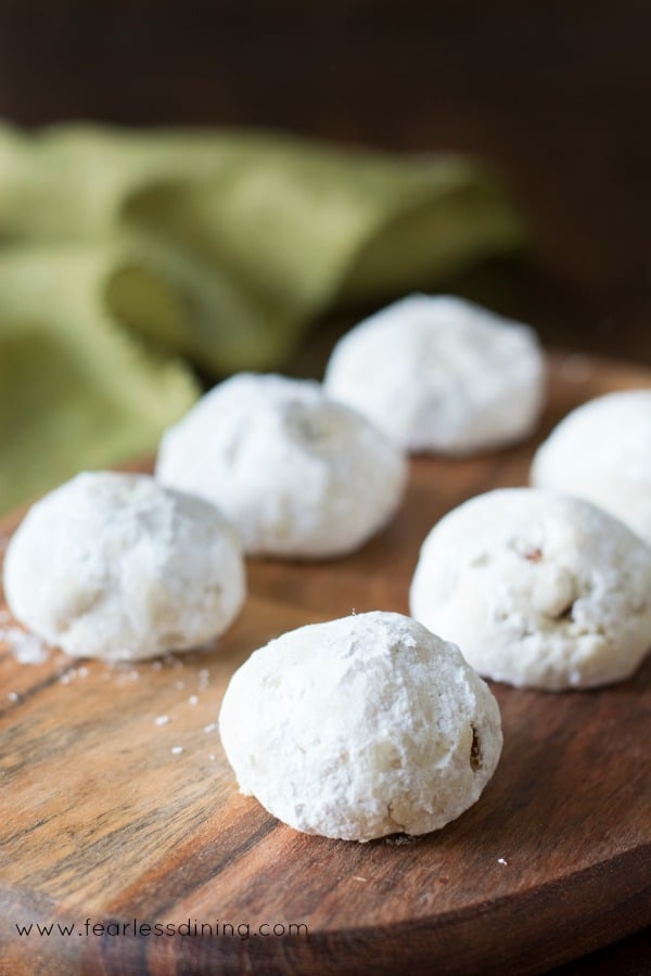 Six gluten free Russian tea cookies on a wooden platter.