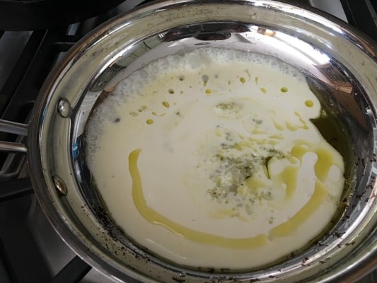 Simmering homemade alfredo sauce in pan.