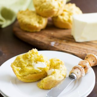 A gluten free cornbread muffin cut open on a plate.