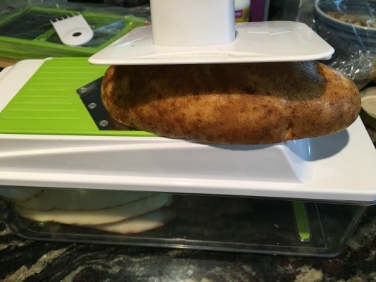 Slicing potatoes with a mandolin slicer.