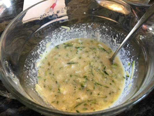 zucchini shreds with eggs, milk, and oil in a bowl