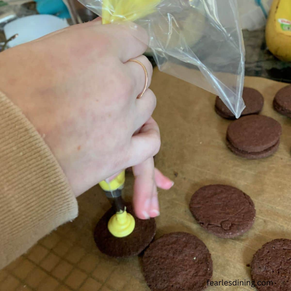 Piping yellow frosting onto a cookie.