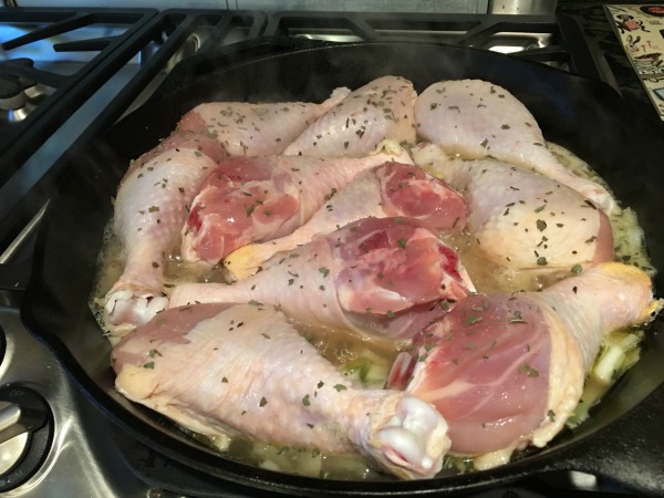 Raw Chicken drumsticks and seasonings in a pan.