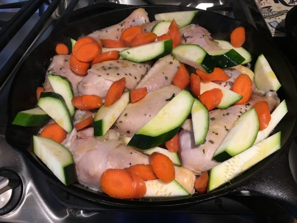 chicken legs, carrots, and zucchini in a pan
