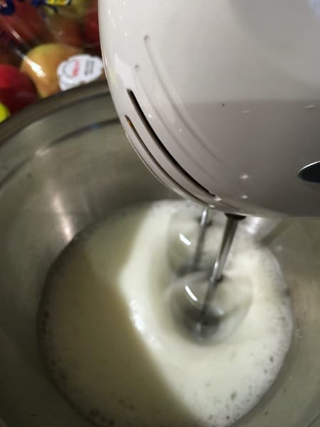 A white electric mixer whipping egg whites into meringue.