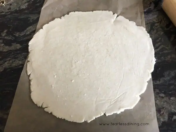 homemade gluten free pie crust dough is rolled into a flat into a circle shape