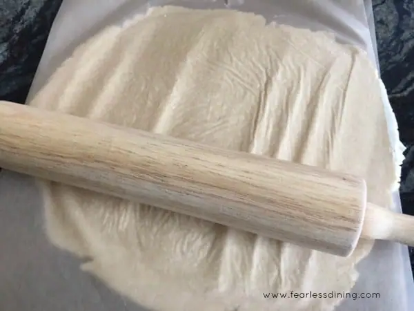 Rolling out gluten free pie crust dough with a rolling pin.