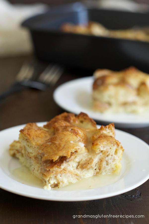 A slice of gluten free bread pudding with vanilla sauce on a plate.