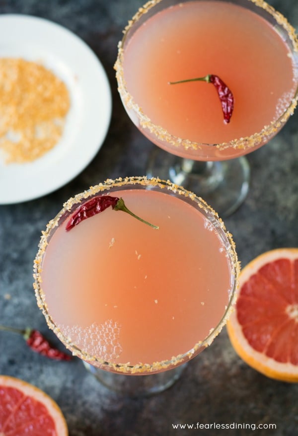 The top view of two pink margaritas next to sliced pink grapefruits.