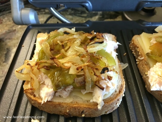 Add grilled onion and hatch chiles to the tuna melt on the panini maker.