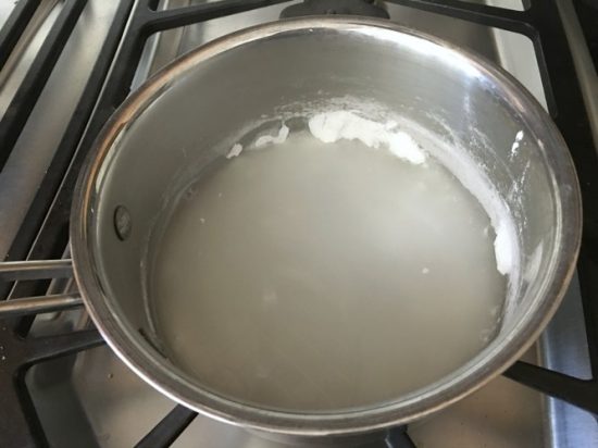 A pot of vanilla sauce ingredients over low heat on a stove.