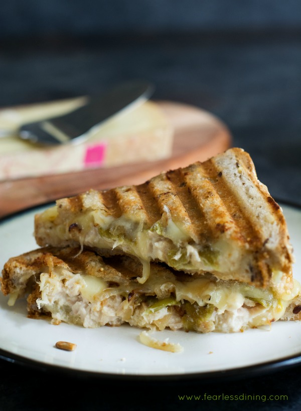Delicious tuna melt panini with grilled onion and hatch chiles sandwich cut in half and stacked on a plate