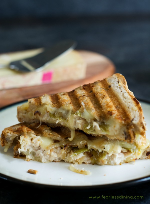 Delicious tuna melt panini with grilled onion and hatch chiles sandwich cut in half and stacked on a plate.