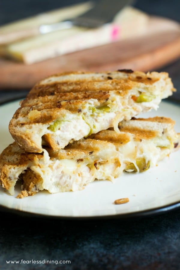 A tuna panini cut in half. The halves are stacked on a white plate.