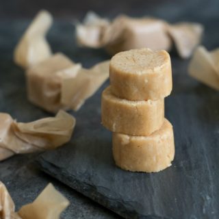 Peanut butter candy stacked on a piece of slate. Wrapped candy is all around the stack.