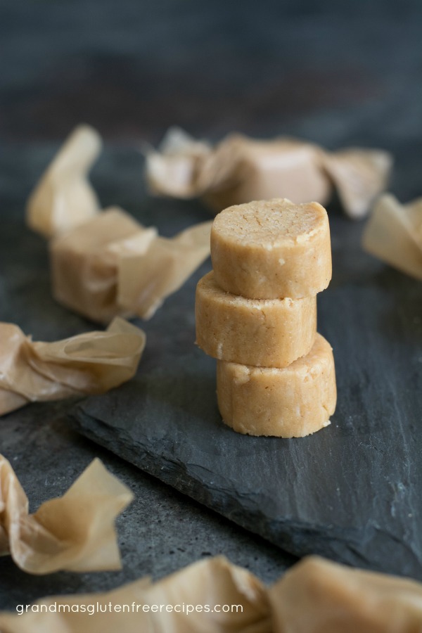 Peanut butter candy stacked on a piece of slate. Wrapped candy is all around the stack.