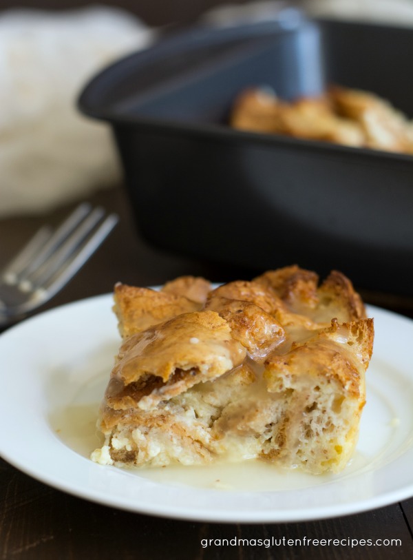 A slice of old fashioned gluten free bread pudding with vanilla cream sauce.