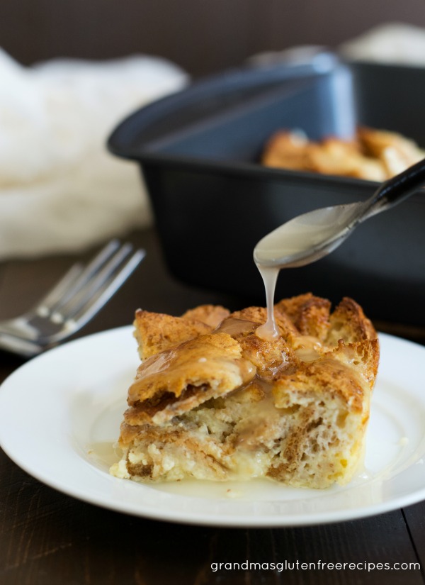 A spoon is drizzling the vanilla cream sauce on top of this gluten free bread pudding!
