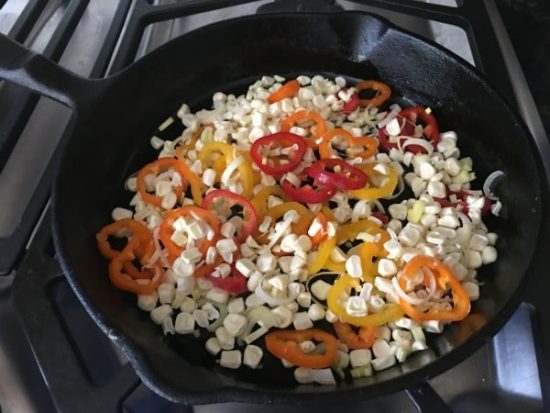 Cooking corn and red peppers in a skillet