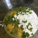 Eggs, cream, and herbs in a bowl, ready to mix.