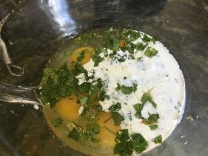Eggs, cream, and herbs in a bowl, ready to mix.
