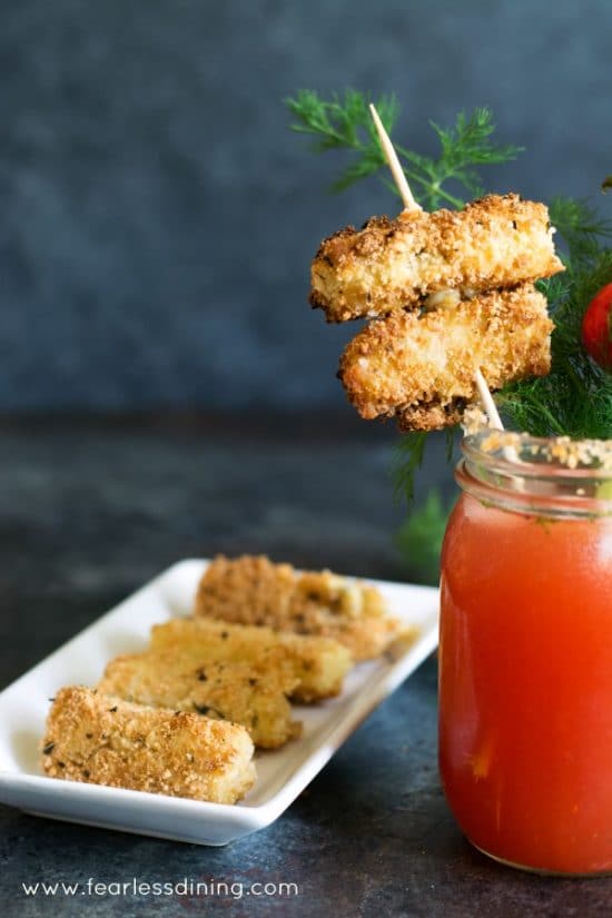 Michelada cocktail next to a plate of homemade gluten free fried mozzarella sticks.