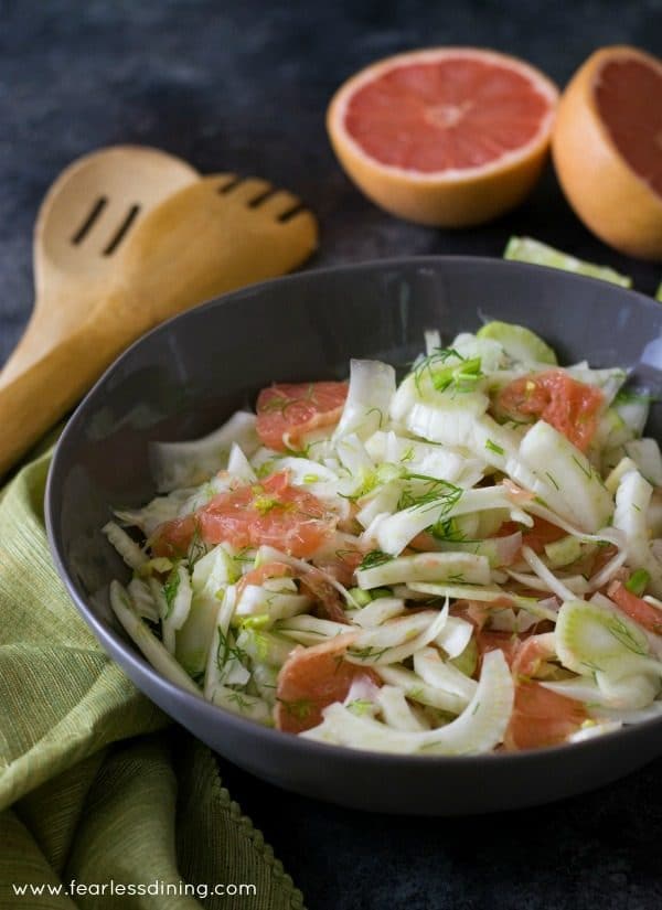A large serving bowl of grapefruit and fennel salad. Sliced grapefruits are in the background