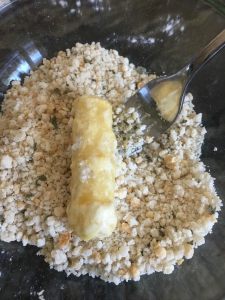 Dipping cheese sticks in gluten free flour, egg, and gluten free bread crumbs.