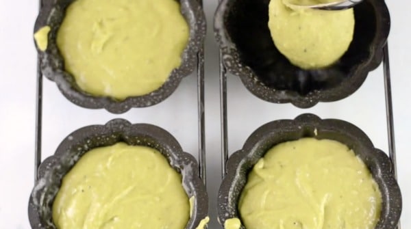 Adding the gluten free matcha bundt cake batter to the mini bundt pans.